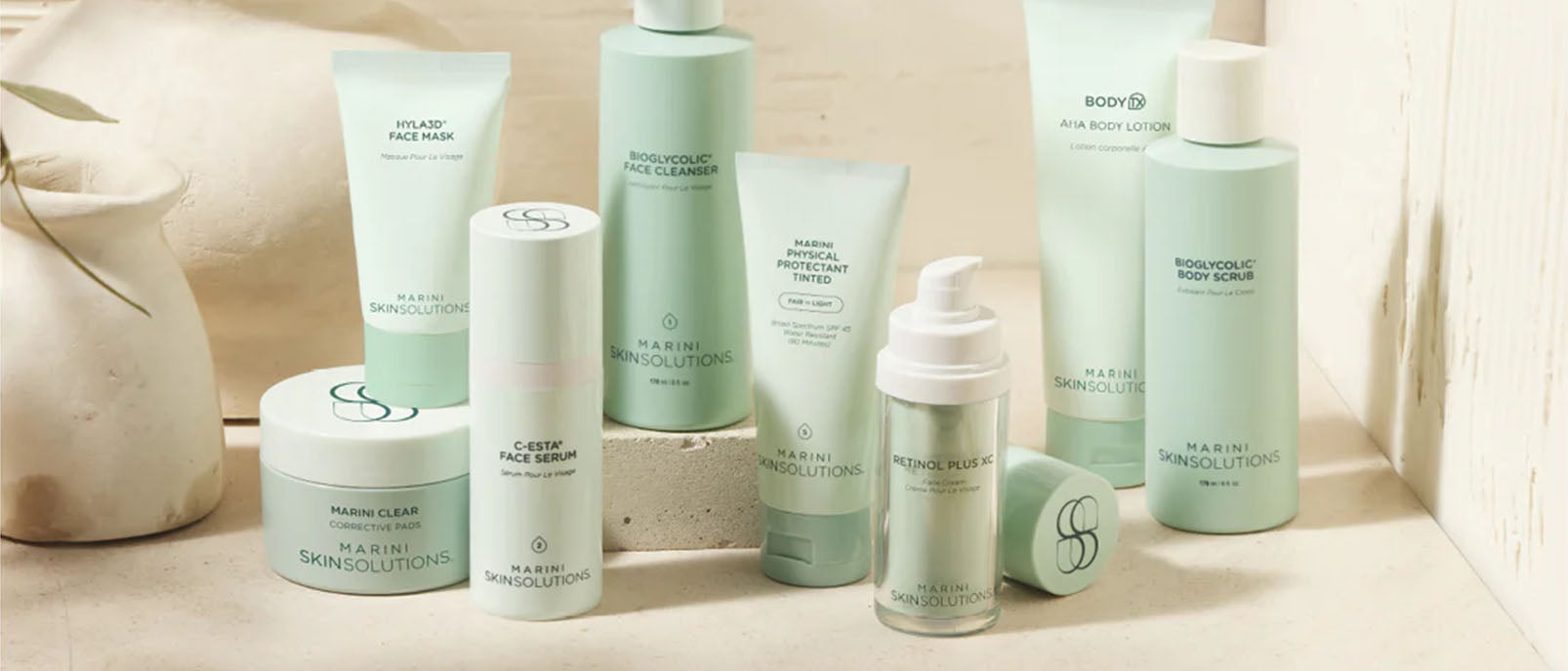 flat lay of multiple Jan Marini creams and serum of a aqua teal blue table