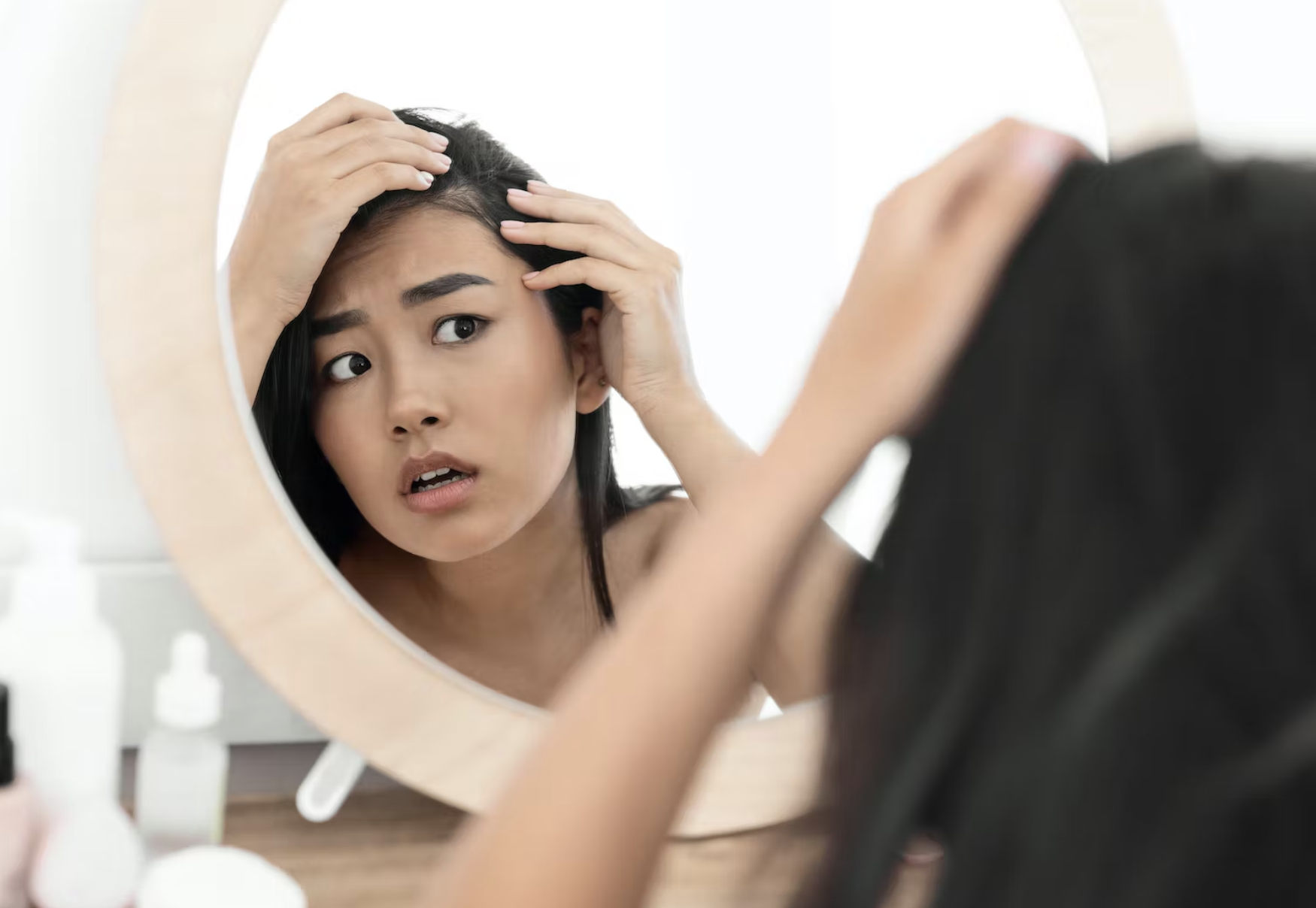 woman looking anxious in a mirror at her hairline