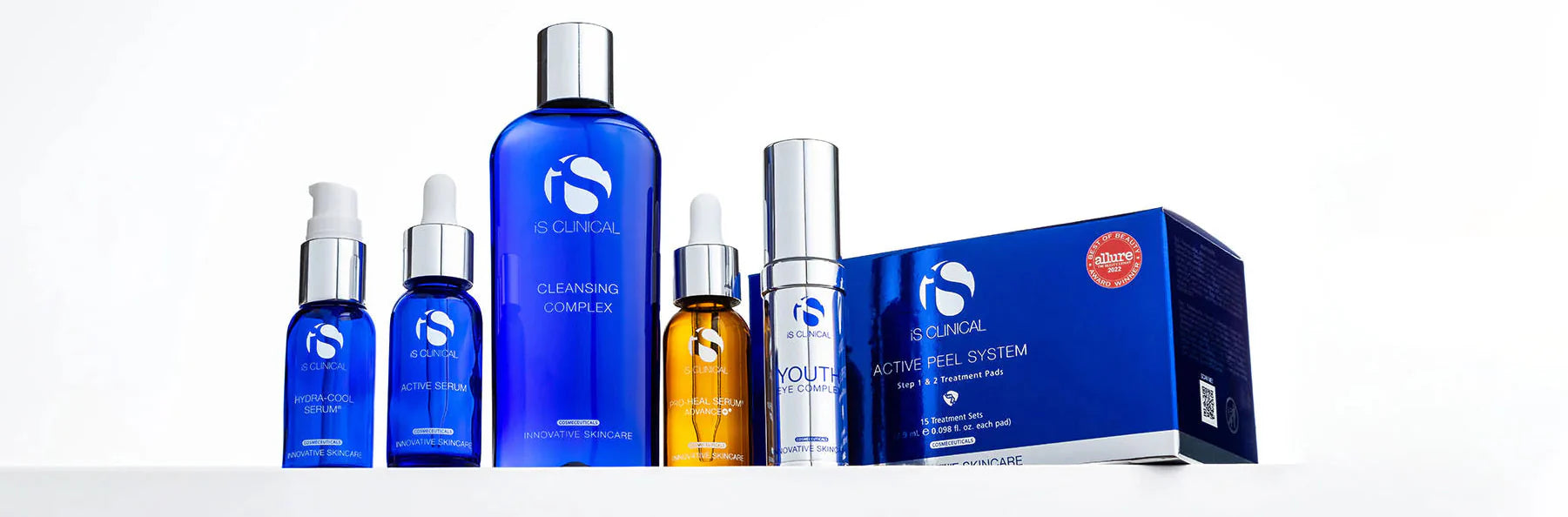 flat lay of three iS Clinical cleansers with water being poured onto them. the products include cream cleanser, cleansing complex, and warming honey cleanser