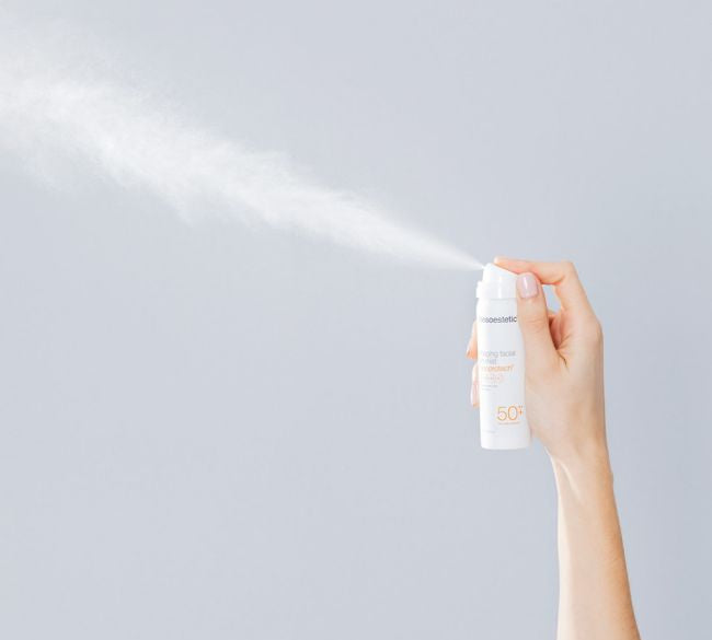 hand holding mesoeesthetic sunscreen spray being sprayed